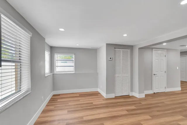 a view of empty room with wooden floor and fan