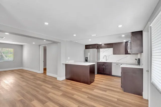 a view of kitchen with stainless steel appliances kitchen island a sink dishwasher a refrigerator and a oven with wooden floor