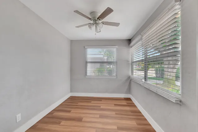 a view of empty room with wooden floor and fan