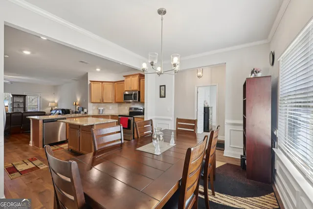 a kitchen with kitchen island a dining table chairs stainless steel appliances and cabinets