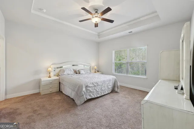 a bedroom with a bed and a large window with ceiling fan
