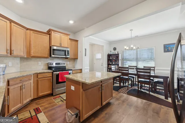 a kitchen with stainless steel appliances granite countertop a stove top oven a sink dishwasher and white cabinets with wooden floor