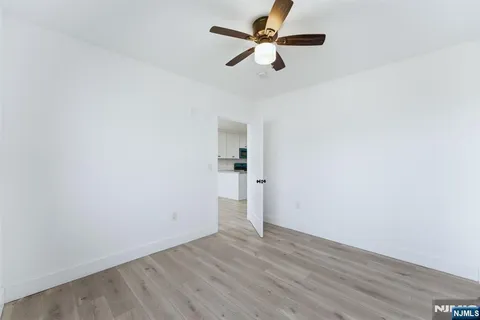an empty room with wooden floor and a ceiling fan
