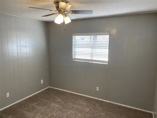 an empty room with a window and a fan
