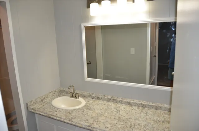 a bathroom with a granite countertop sink and a mirror