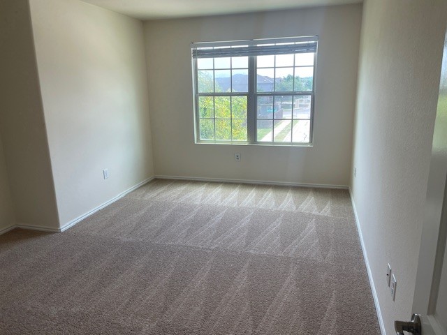 10201 Gertrudis Loop Austin, TX 78747 - Photo 22 of 24 A well-lit bedroom with fresh carpet and ample natural light from a large window.