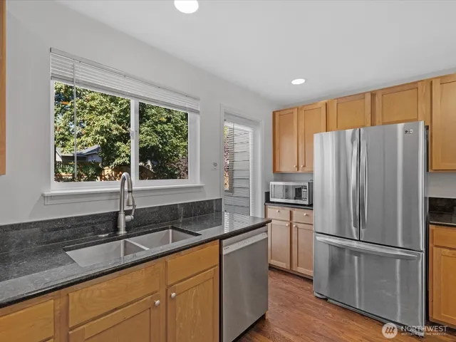 a kitchen with granite countertop stainless steel appliances a refrigerator sink and microwave