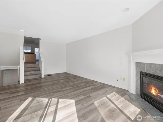 a view of empty room with wooden floor and fireplace