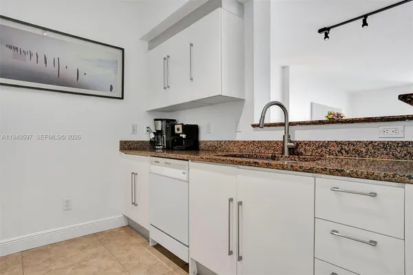 a kitchen with granite countertop white cabinets and white appliances