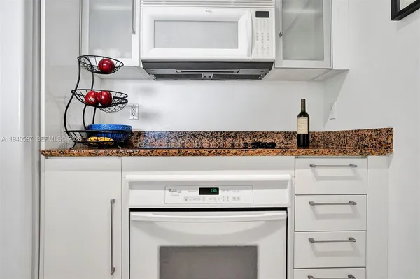 a view of white cabinets and dresser with wooden floor