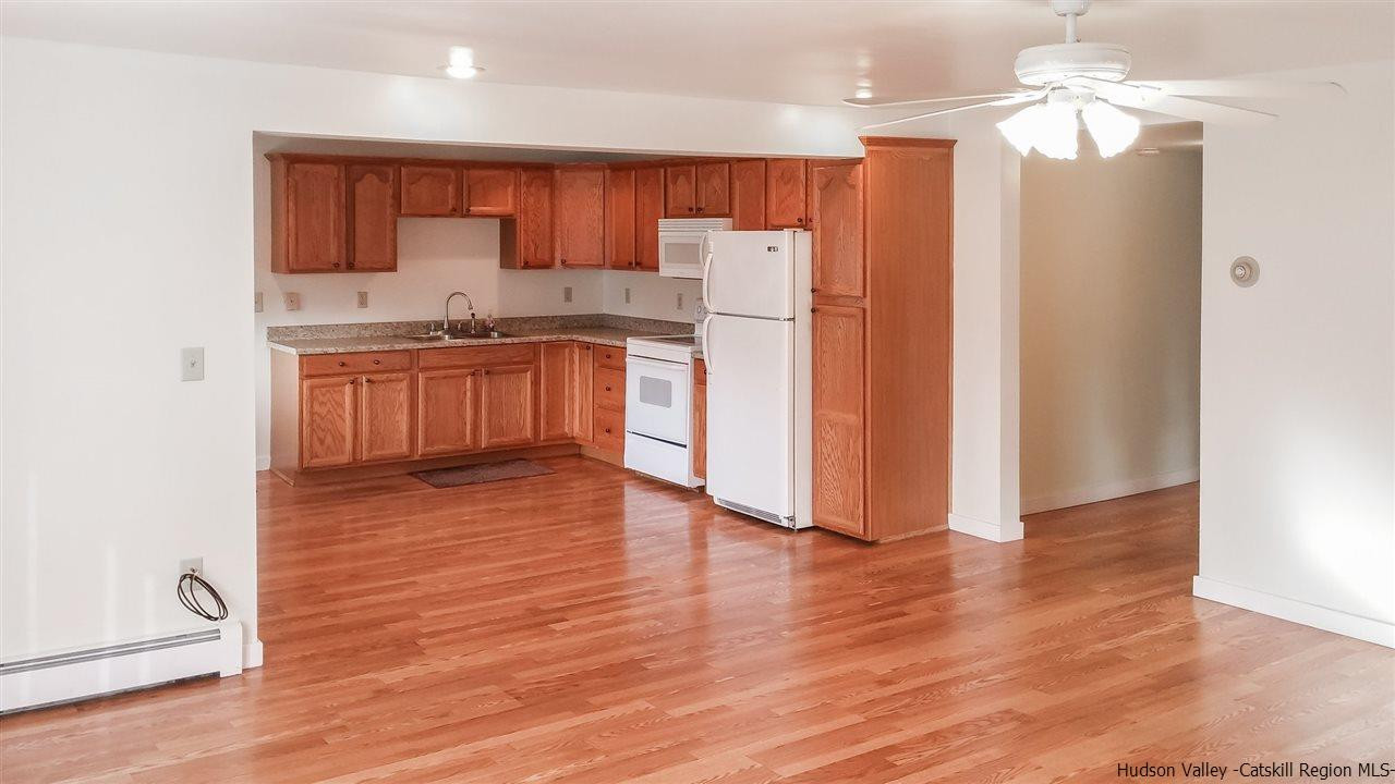 735 Springtown Road Tillson, NY 12486 - Photo 7 of 35 a kitchen with kitchen island granite countertop wooden floors white cabinets and stainless steel appliances