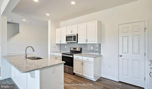 a kitchen with granite countertop a sink stove and microwave