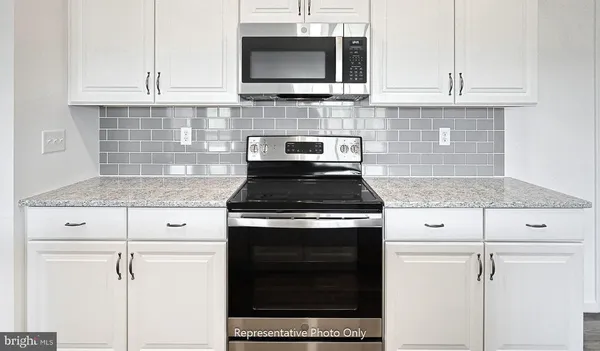 a kitchen with granite countertop white cabinets and stainless steel appliances