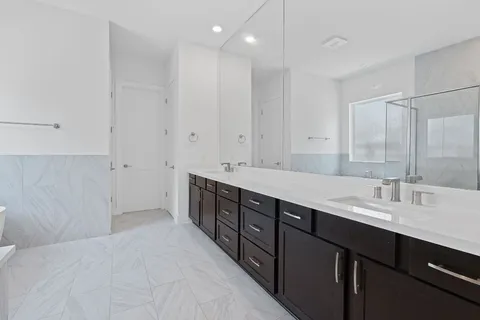a spacious bathroom with double vanity and a mirror