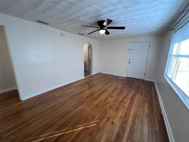 a view of empty room with wooden floor and fan