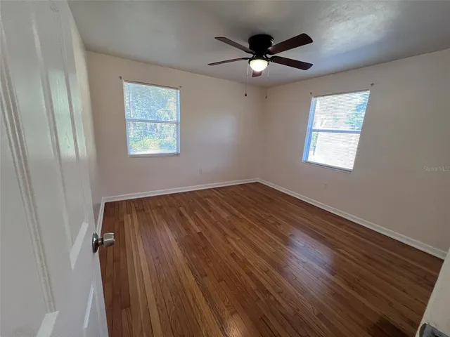 a view of an empty room with a window and wooden floor