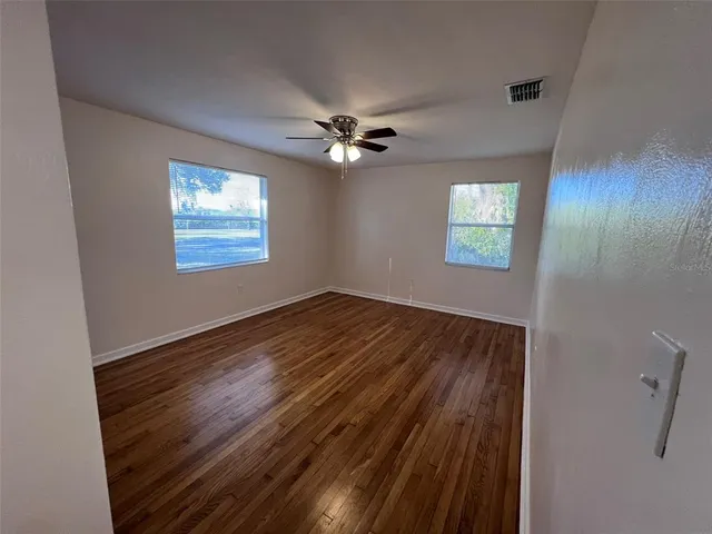 a view of empty room with wooden floor and fan
