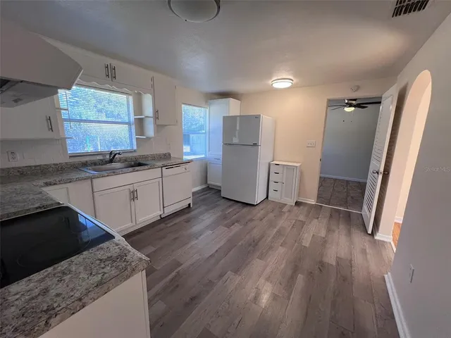 a kitchen with a sink a refrigerator and wooden floor