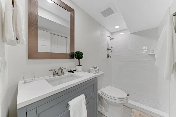 a bathroom with a sink a toilet a mirror and shower