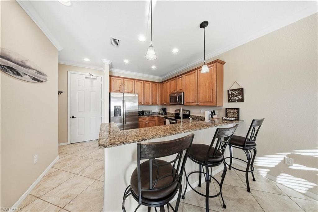 9063 Capistrano Street North, Unit 4401 Naples, FL 34113 - Photo 29 of 50 a kitchen with stainless steel appliances granite countertop a dining table chairs and white cabinets