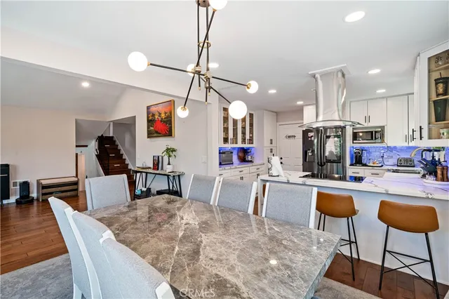 a kitchen with stainless steel appliances kitchen island granite countertop a dining table chairs and white cabinets