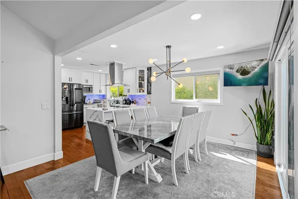 a dining room with furniture a potted plant and kitchen view