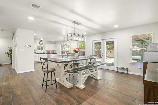 a kitchen with stainless steel appliances kitchen island granite countertop a table chairs sink and cabinets