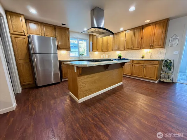 a kitchen with granite countertop wooden floors stainless steel appliances and a counter