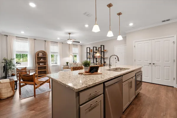 a kitchen with granite countertop a stove a sink a dining table and chairs with wooden floor