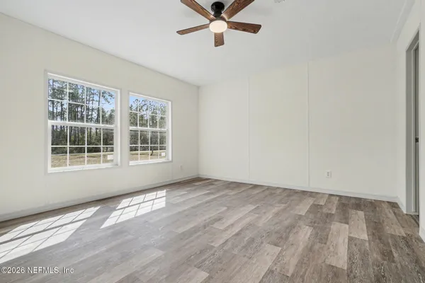 an empty room with wooden floor fan and windows