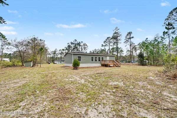 a view of house with yard and trees in the background