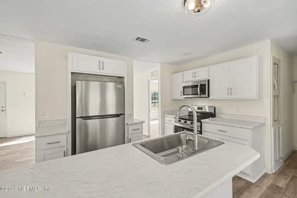 a kitchen with a refrigerator sink and white cabinets