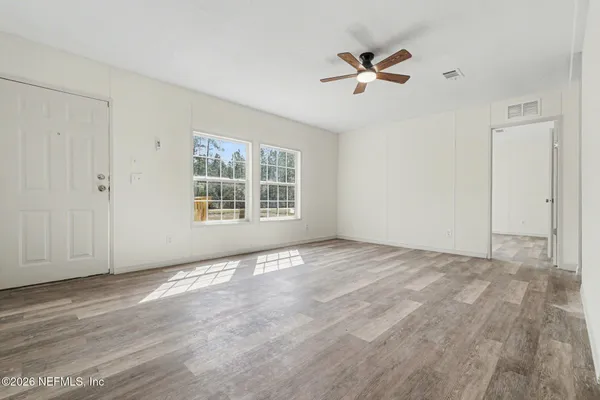 a view of an empty room with wooden floor and a window