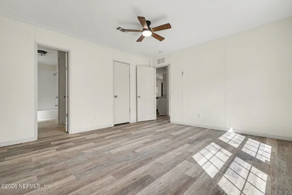 an empty room with wooden floor and ceiling fan