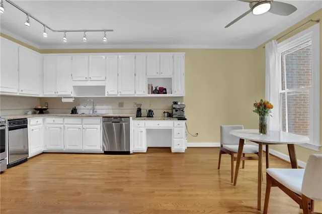 a kitchen with stainless steel appliances white cabinets and wooden floor
