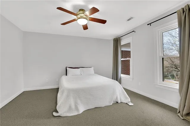 a bedroom with a large bed and a chandelier fan
