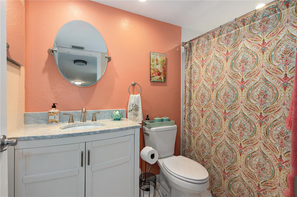 1512 Pelican Cove Road, Unit 239 Sarasota, FL 34231 - Photo 15 of 29 a bathroom with a granite countertop toilet sink and mirror