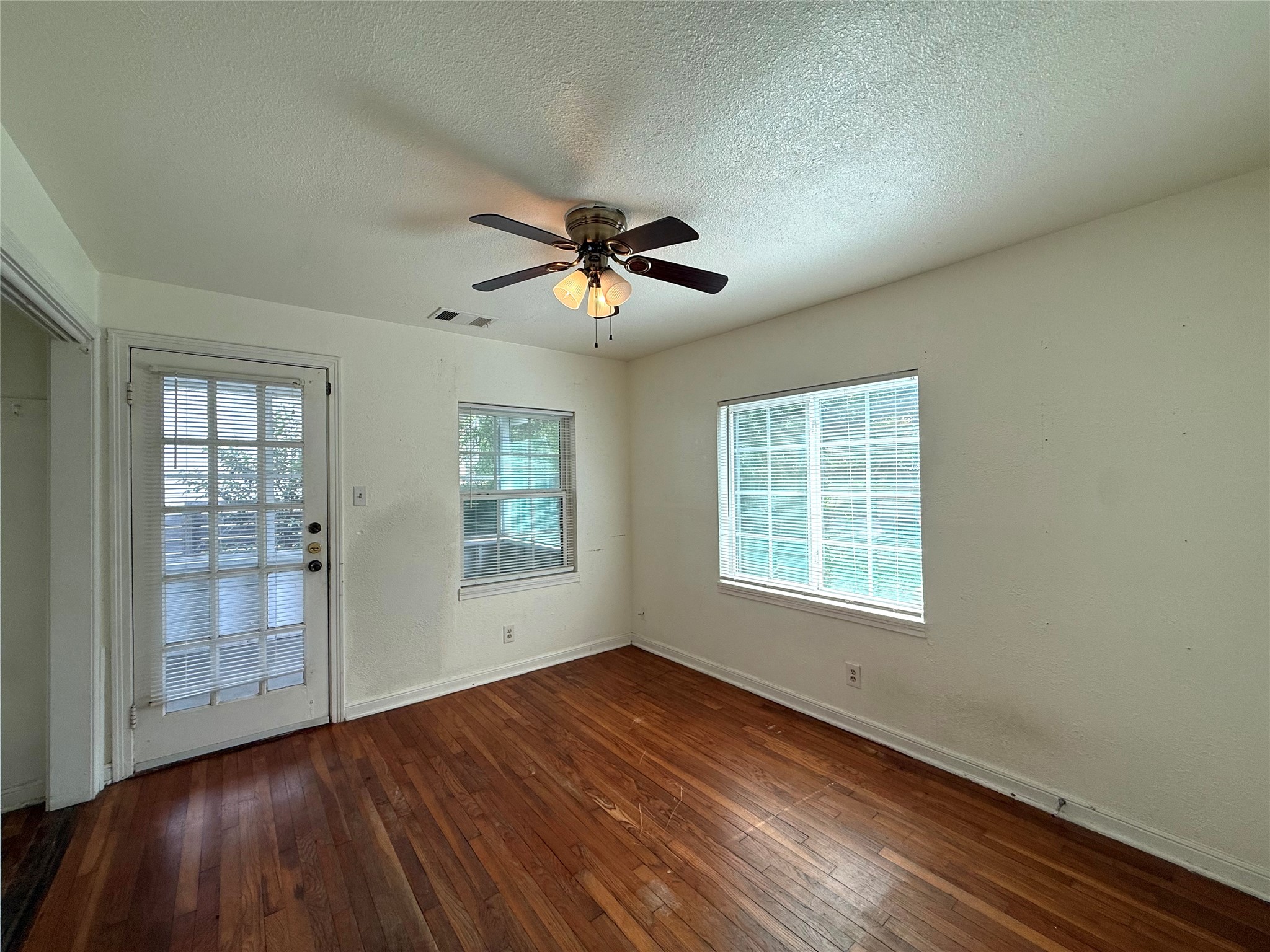 3305 Merrie Lynn Avenue Austin, TX 78722 - Photo 11 of 22 Rich hardwood floors complement this room, featuring ample natural light from multiple windows and a convenient exterior door.