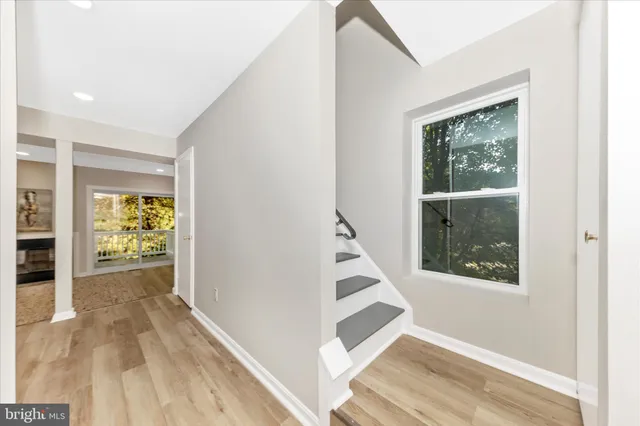 a view of a hallway to a bedroom with wooden floor and a window