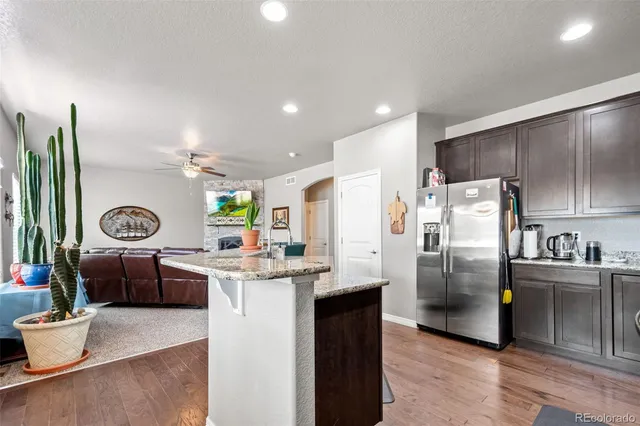 a kitchen with stainless steel appliances kitchen island granite countertop a refrigerator a stove a sink and a refrigerator with wooden floor