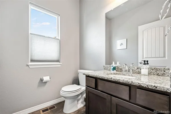 a bathroom with a granite countertop toilet sink and mirror