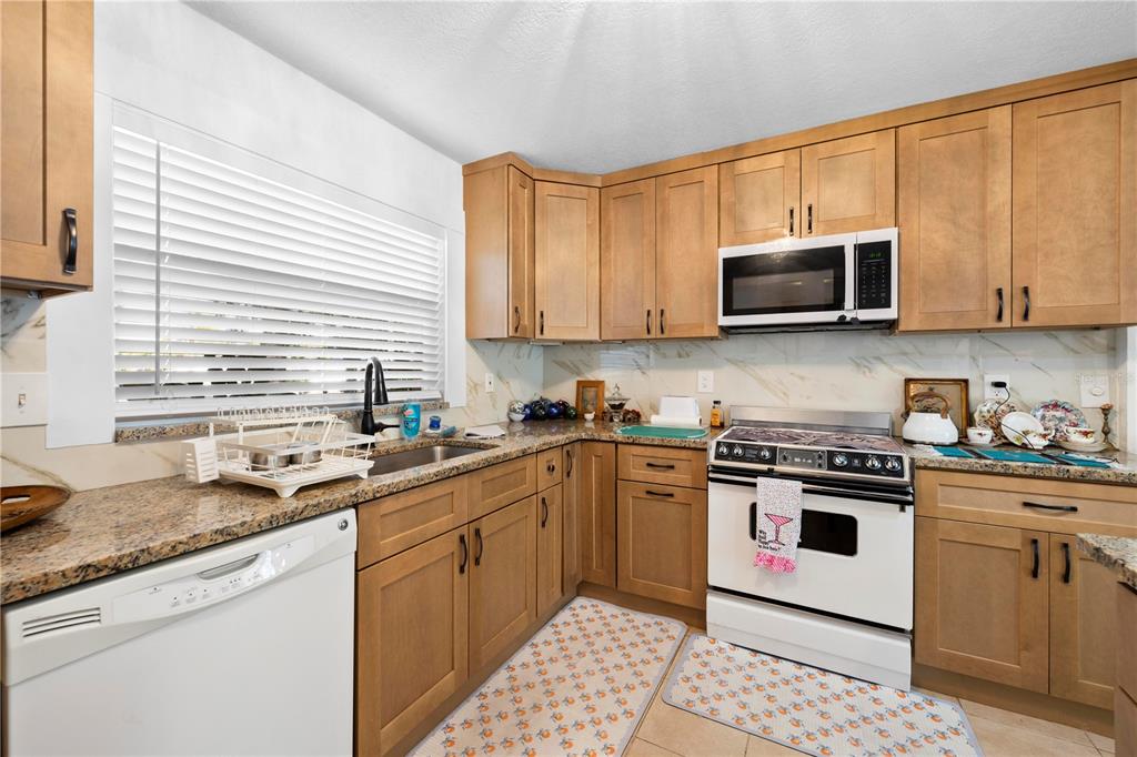 5122 Bay Boulevard Port Richey, FL 34668 - Photo 7 of 56 a kitchen with stainless steel appliances granite countertop a stove sink microwave and refrigerator