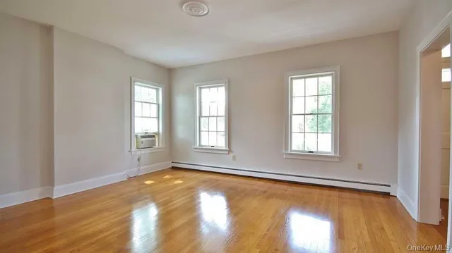 a view of empty room with wooden floor and fan