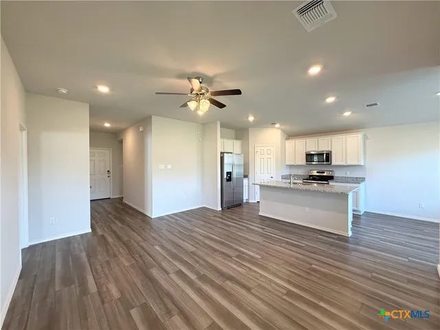 a view of kitchen with kitchen island stainless steel appliances refrigerator stove microwave and cabinets