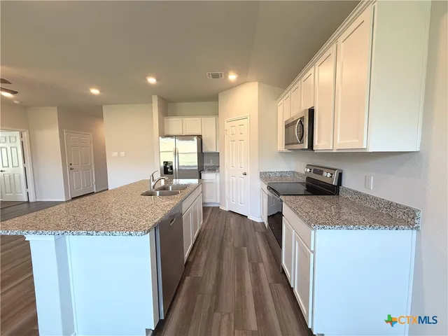 a kitchen with stainless steel appliances granite countertop a sink stove and refrigerator