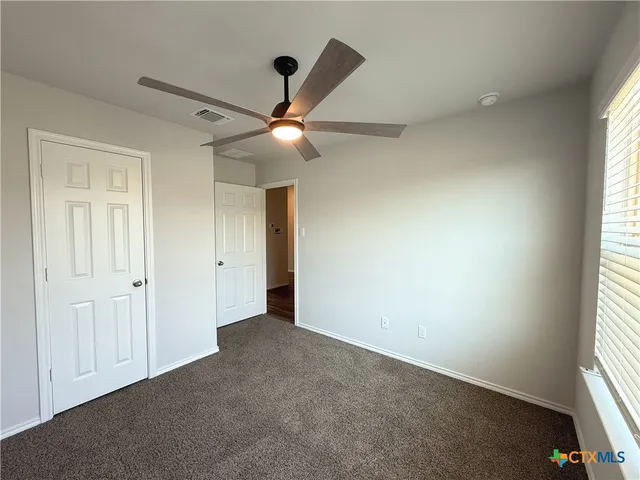 an empty room with a window and ceiling fan