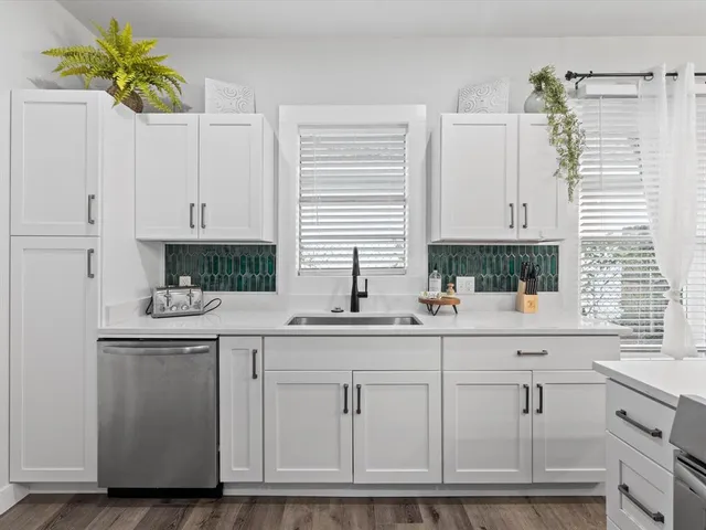 a kitchen with white cabinets and sink