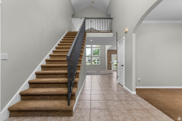 1417 Blacksmith Lane Draper, UT 84020 - Photo 3 of 57 Two-story entryway featuring a carpeted staircase with dark iron balusters, tiled flooring, vaulted ceilings, and an arched doorway