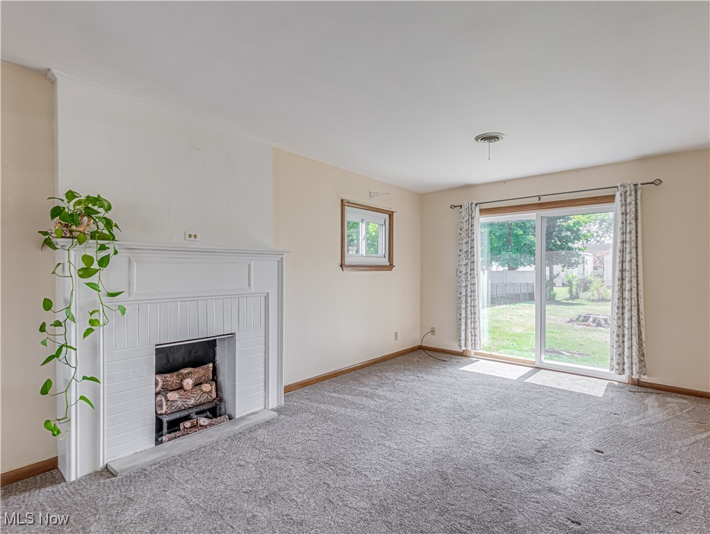 1014 Lilly Road Alliance, OH 44601 - Photo 3 of 19 Unfurnished living room with carpet floors and a brick fireplace