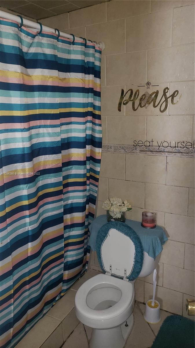 559 Dogwood Road West Palm Beach, FL 33409 - Photo 5 of 7 a bathroom with a sink a toilet and shower curtain